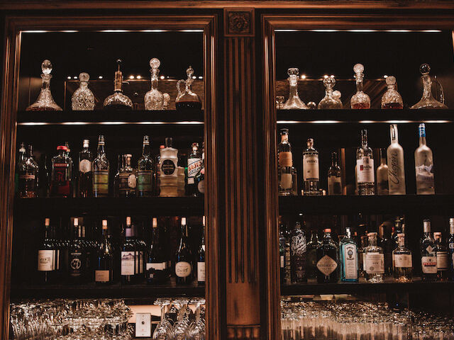 A well-stocked bar with various bottles and glasses on shelves.