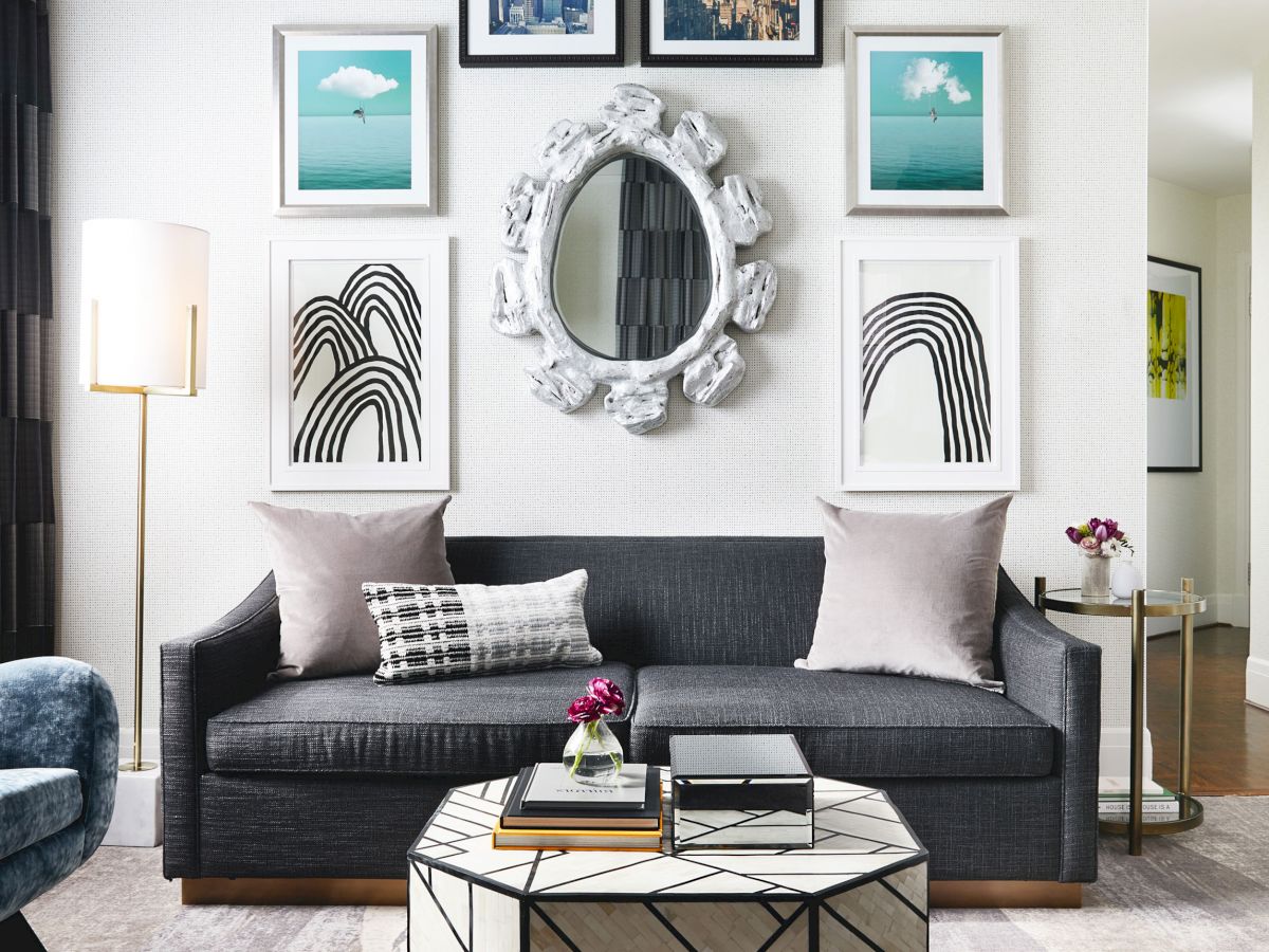 A cozy, modern living room with a gray sofa, assorted artwork, decorative pillows, a geometric coffee table, and contemporary lighting.