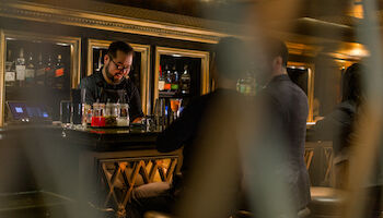 Bartender serving two guests a cocktail at Le Parc Bistrobar