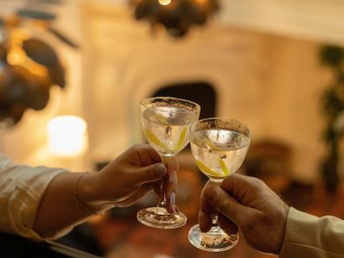 Two people toasting with glasses of champagne in an elegant, warmly lit setting with a blurred background.