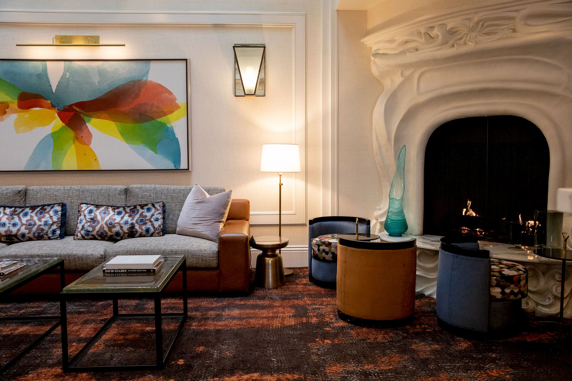 A cozy living room featuring a modern fireplace, colorful abstract art, a comfortable sofa, and stylish furniture.