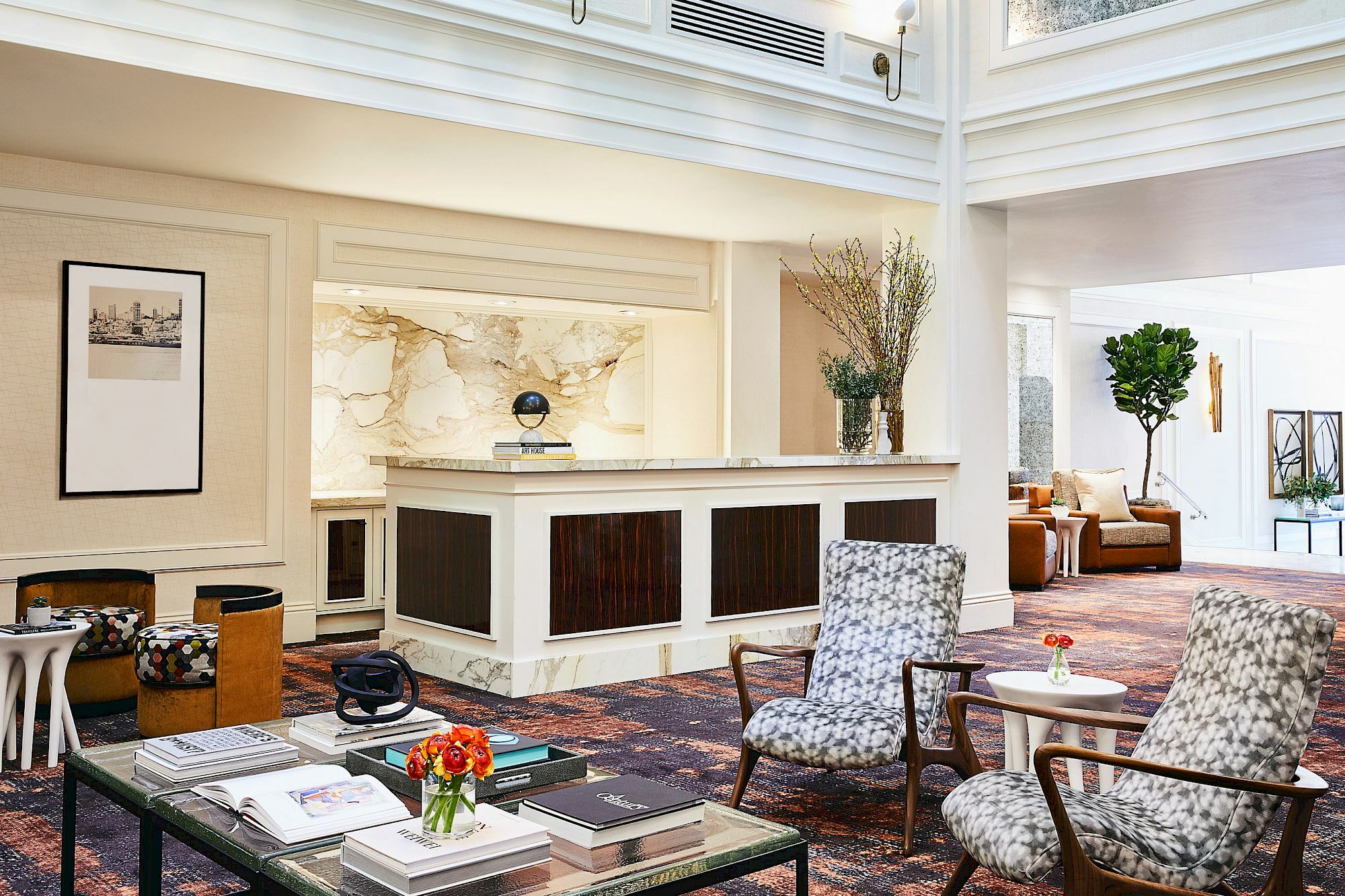 A stylish lobby with patterned chairs, a reception desk, books, and decor, creating a welcoming and elegant atmosphere.