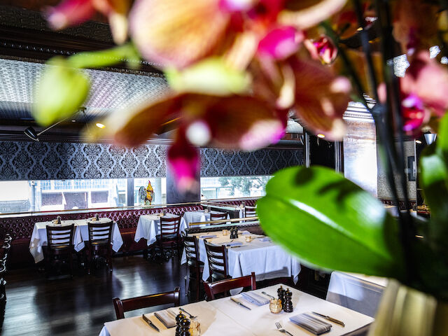 A restaurant dining area with tables set for dinner and flowers in the foreground.