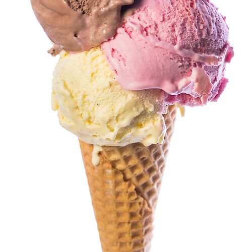 A waffle cone holds three ice cream scoops: chocolate, strawberry, and vanilla, stacked neatly on top of each other.