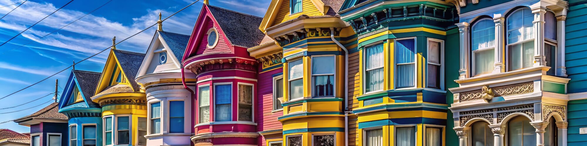 A row of colorful, ornate Victorian-style houses under a clear blue sky, showcasing vibrant architectural details.