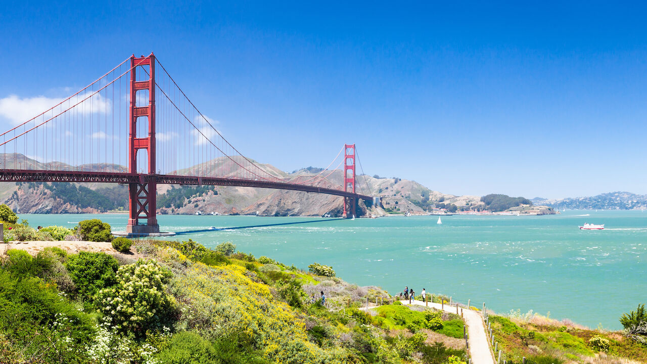 A scenic view of the Golden Gate Bridge with a pathway and hills in the foreground.