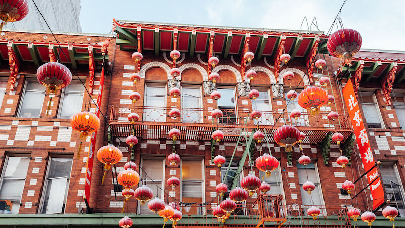 A red brick building with many red lanterns and Chinese characters on it.