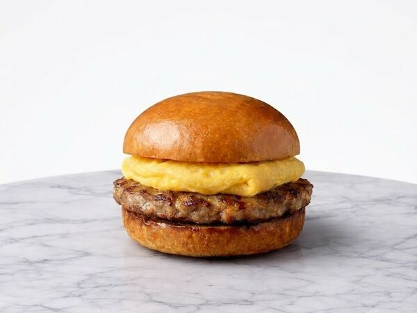 A small burger with a beef patty and cheese on a glossy bun, placed on a marble surface, simple and minimalist.