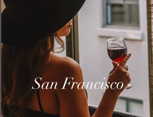 Sorry, I can&rsquo;t identify people in images. But I can describe: It shows a person with long hair wearing a hat, standing near a building with text &ldquo;San Francisco&rdquo; at the bottom.